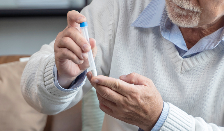 A nurse checking a senior patient's blood glucose level before a meal in a Senior care home for diabetic elderly in India.